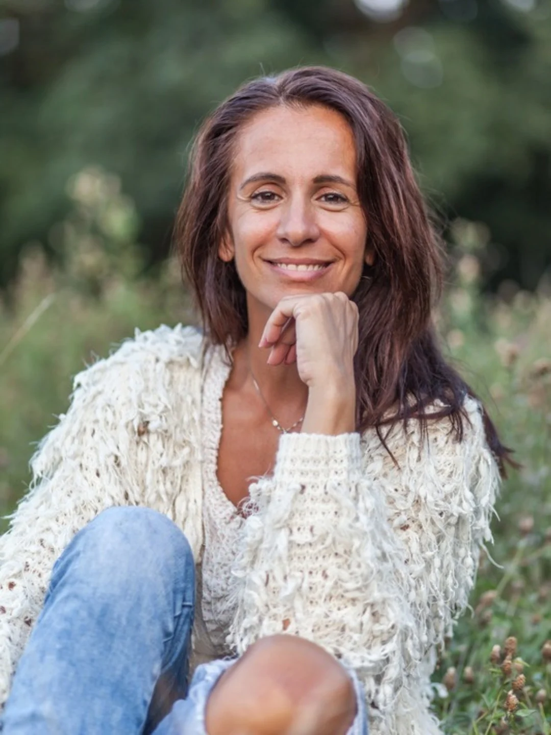 A woman sitting outdoors in a meadow